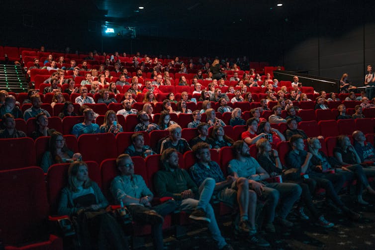 A crowd of people watching a film inside a movie theatre