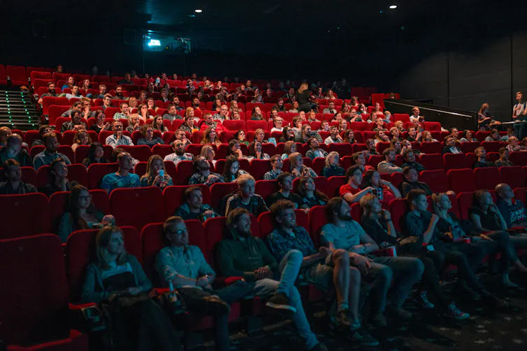 A crowd of people watching a film inside a movie theatre