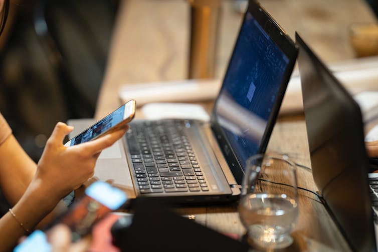 A person using a laptop and smartphone simultaneously