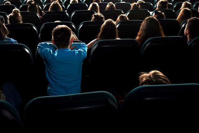 A young boy watching a film in the theatre