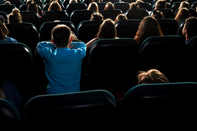 A young boy watching a film in the theatre