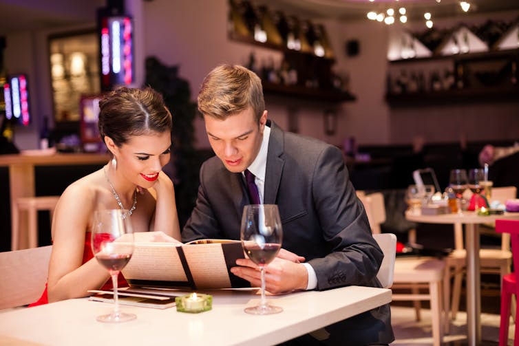 Couple reading a menu at a restaurant table.