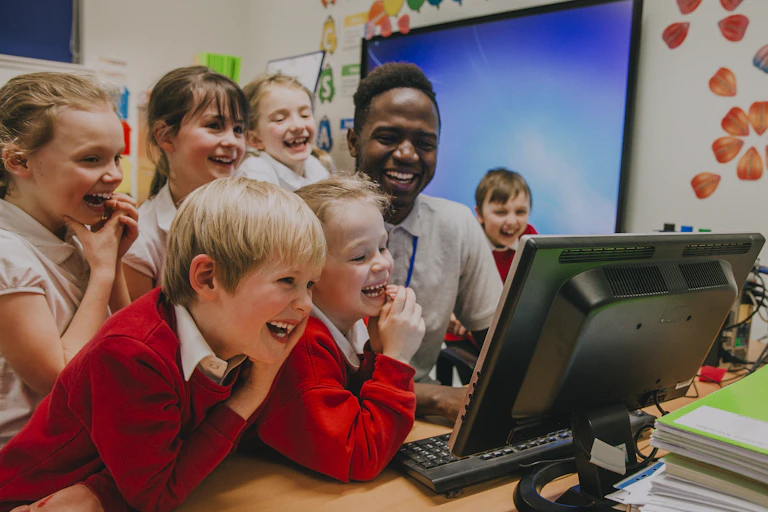 Teacher and pupils laughing at computer