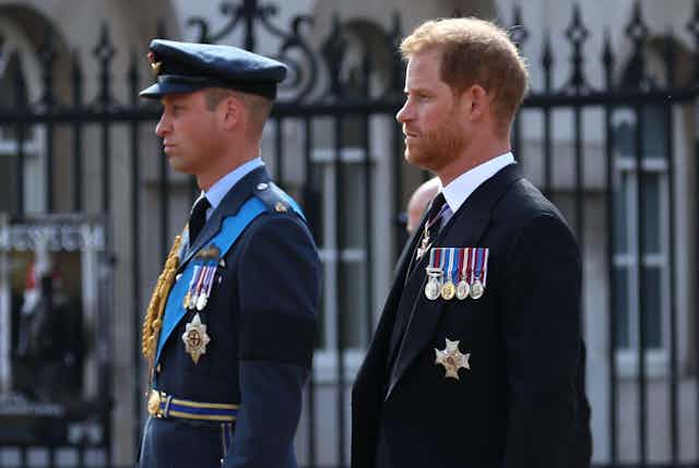 William and Harry standing side by side during a formal procession, staring straight ahead