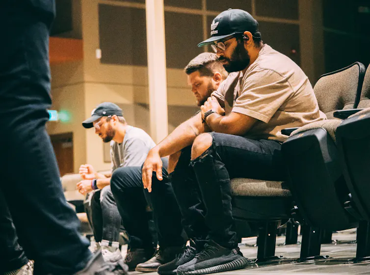 Three men sit in prayer in a church.