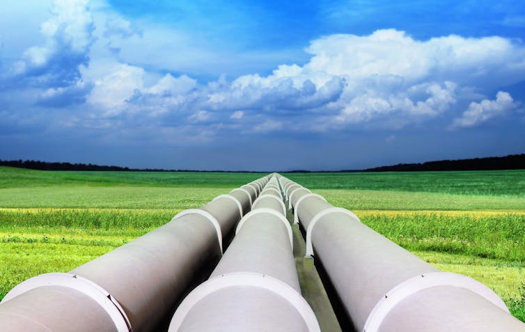 pipeline extends across flat grassy land to horizon