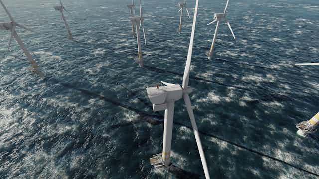 Aerial shot looking down at white offshore wind turbines, waves breaking on surface of blue sea
