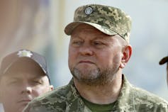 A broad-faced man in a camouflage ball cap.