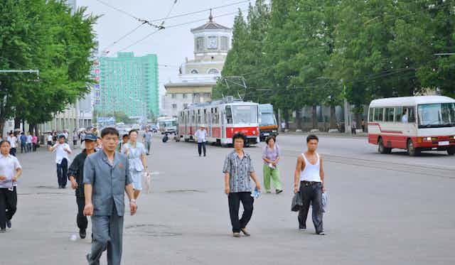A small group of North Korean men and women walking down a city street.