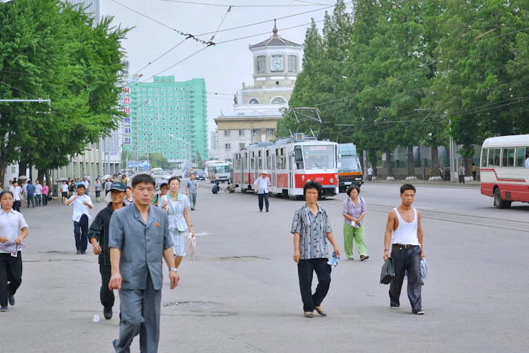 A small group of North Korean men and women walking down a city street.