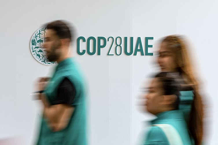 People walk past COP28UAE sign