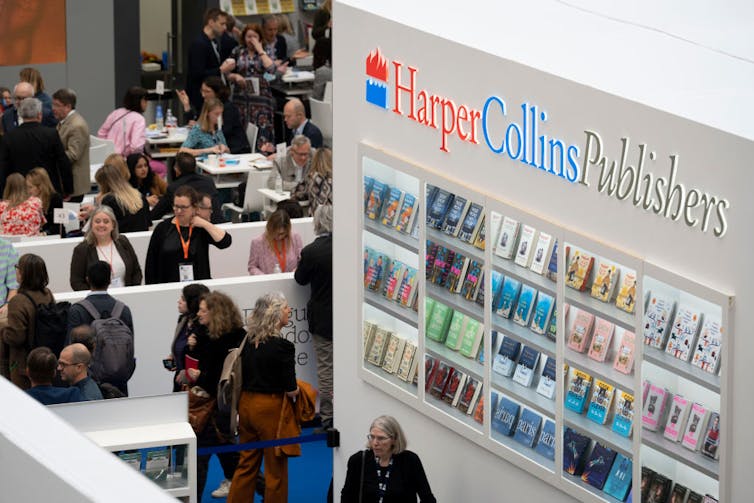 Multitudes de personas exploran la exposición de HarperCollins en una feria del libro.