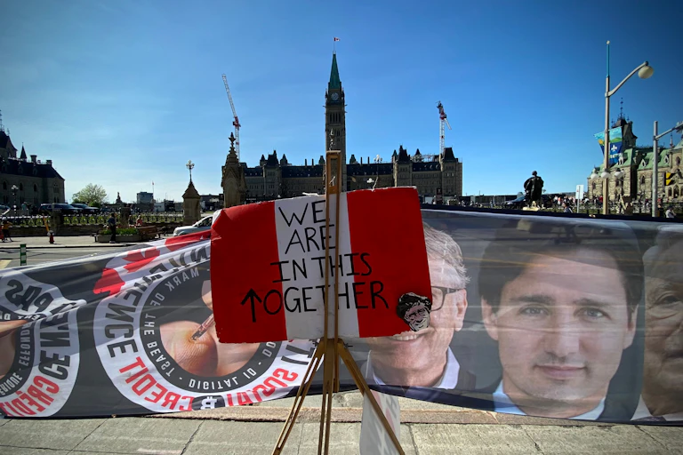 Signs and banners displayed in front of a large building.
