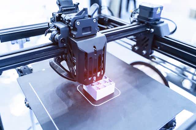 A metal 3D printer printing a small box. 