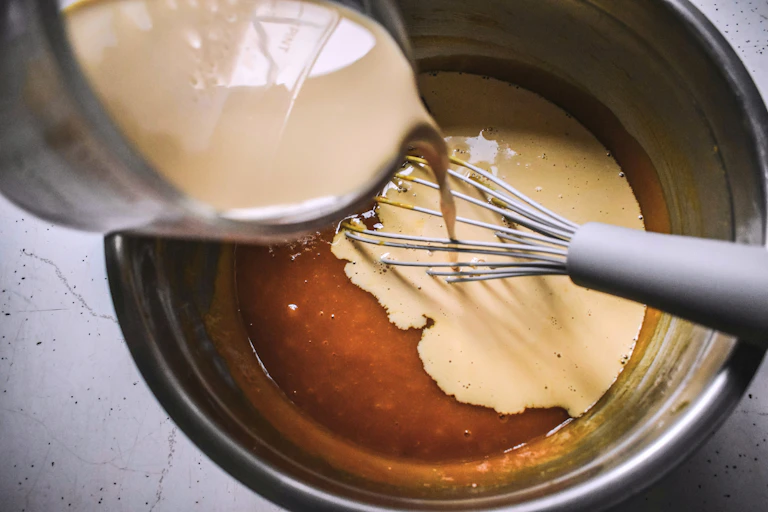 A bowl with chocolate batter and cream being poured into it