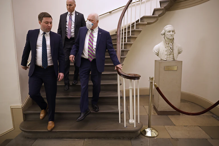 Three men in suits walking down a set of curving stairs.