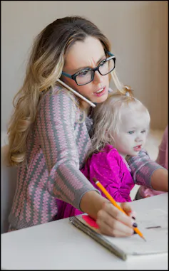 Photo of woman on computer while holding child