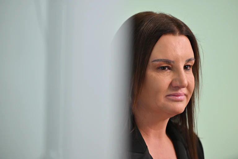Jacqui Lambie walking past a wall