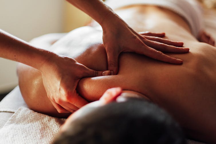 Massage therapist massaging woman's back