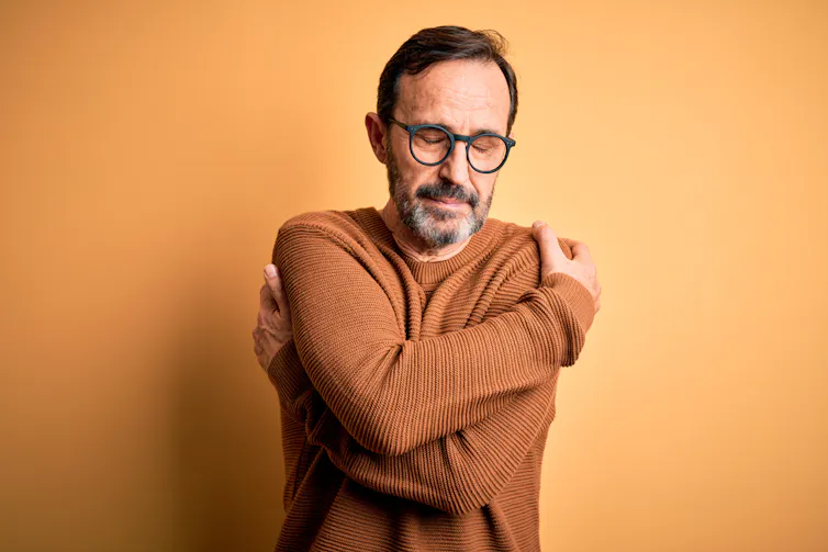Middle-aged man hugging himself