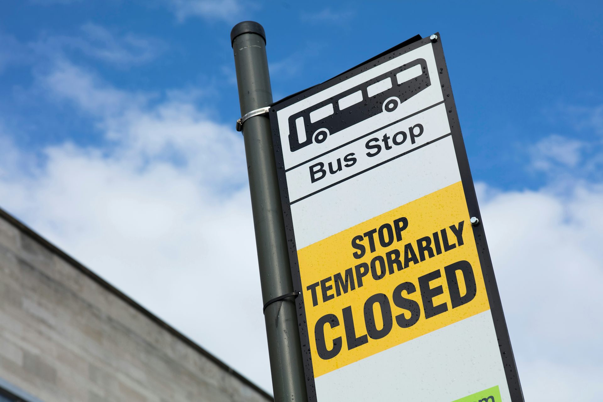 Photo of a bus stop temporarily closed sign against a blue sky