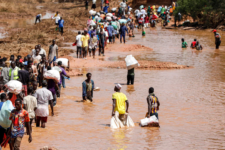 People walking through murky, muddy waters.