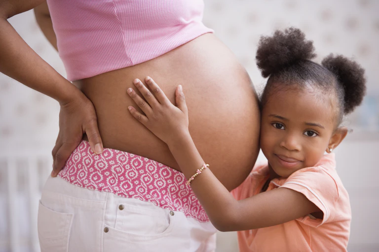 Young child touches a woman's pregnant belly