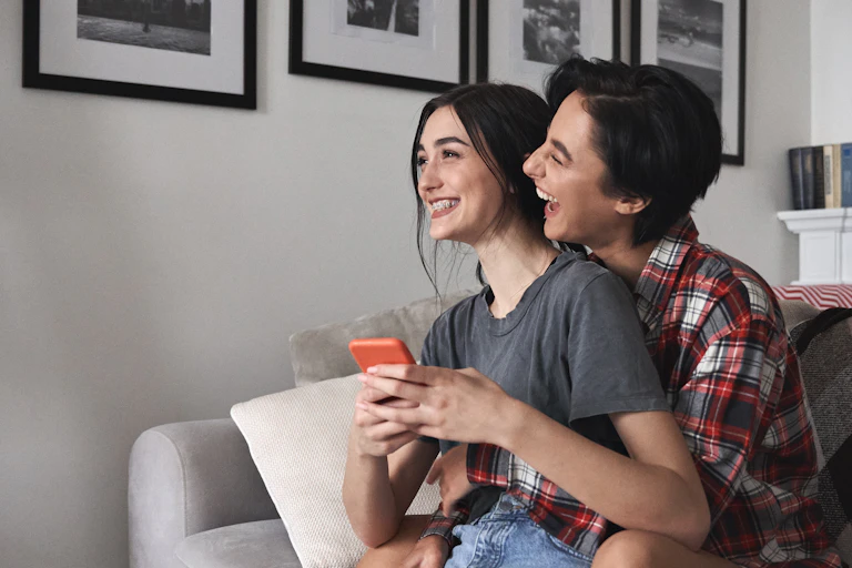 A couple laughs inside an apartment.