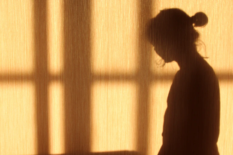 Shadow of a young woman against a yellow wall