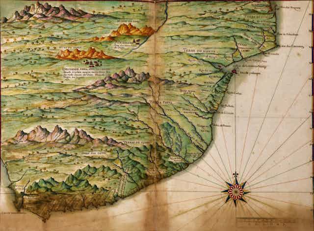 An old map in colour with cursive names in Portuguese showing a coastline and hilly interior.