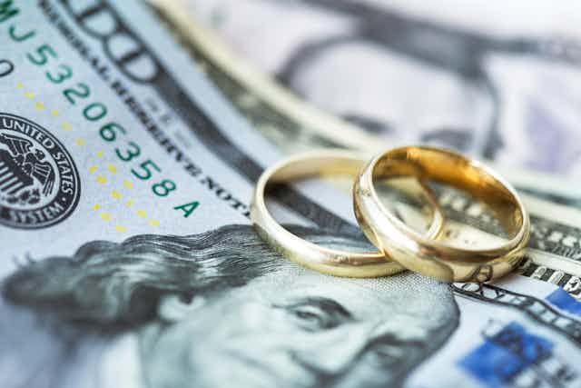 Two gold wedding rings atop US bills
