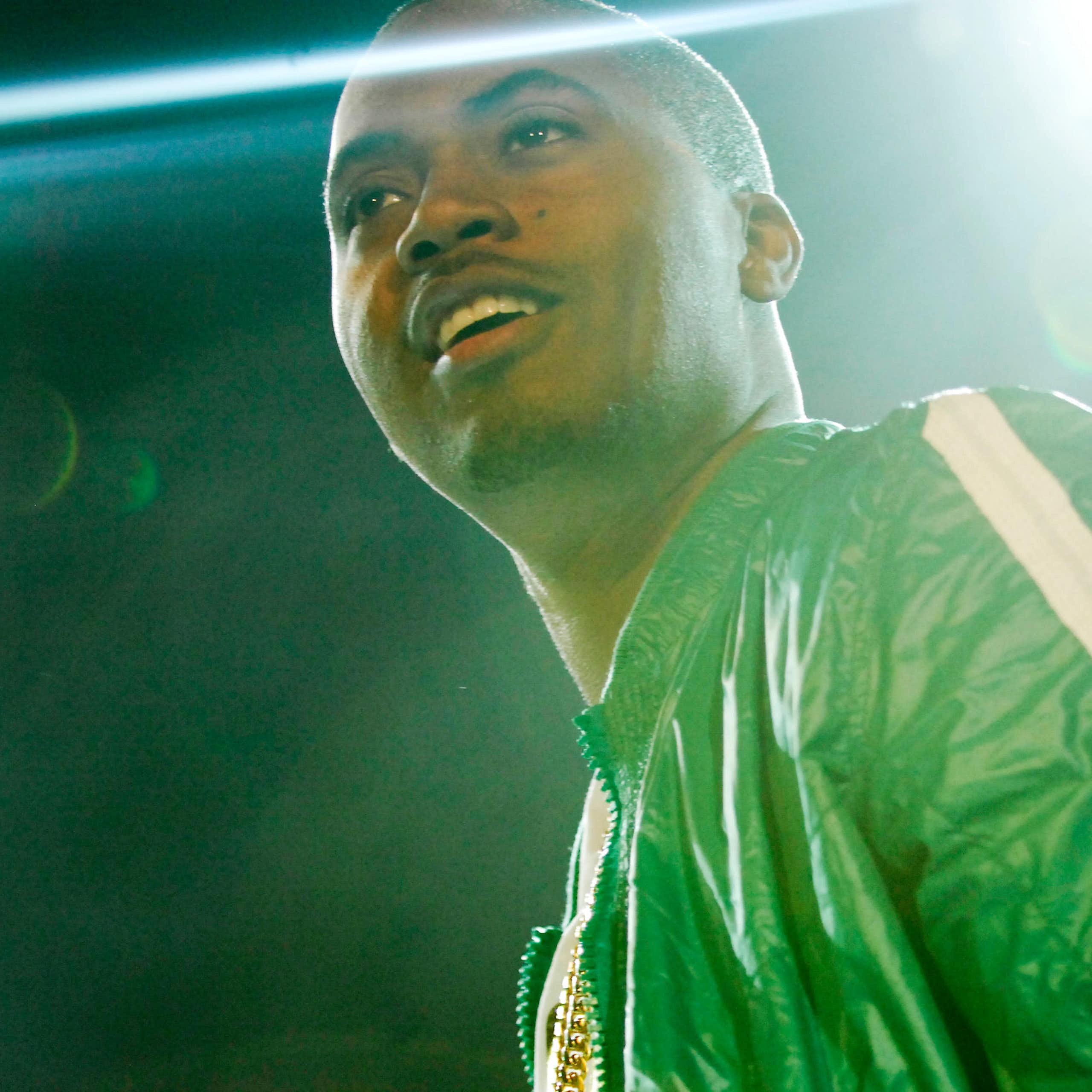 Nas on stage in a green jacket