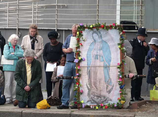 Anti-abortion activists congregating outside an abortion clinic with a large image of the Virgin Mary