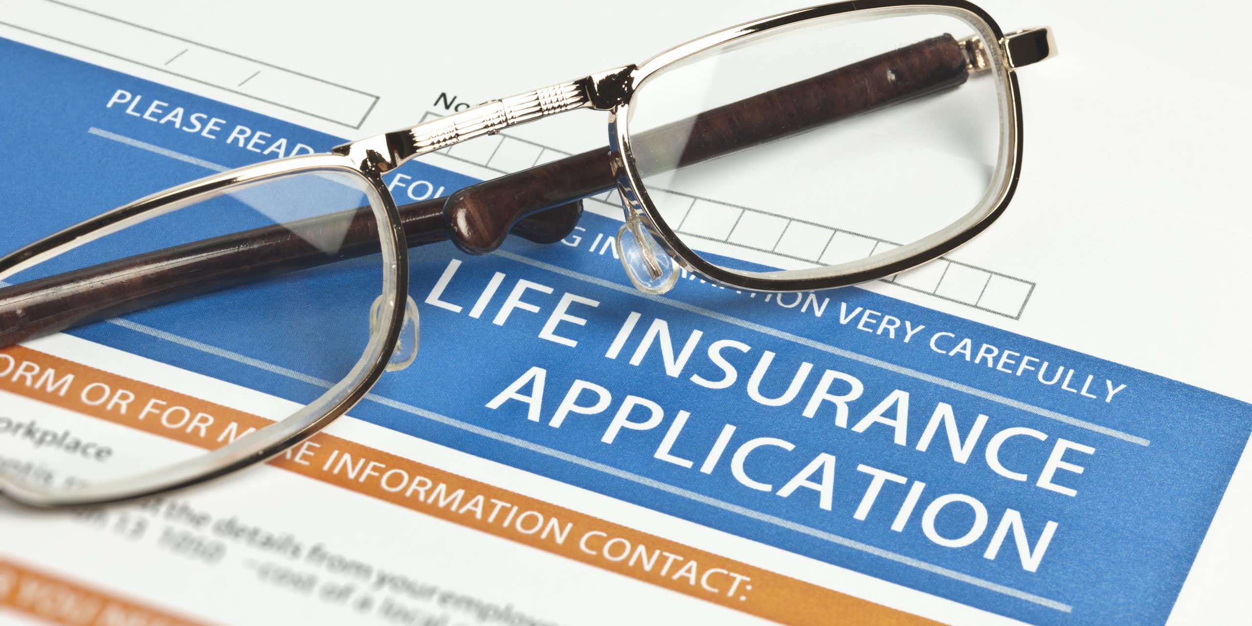 a pair of reading glasses rests on a life insurance application