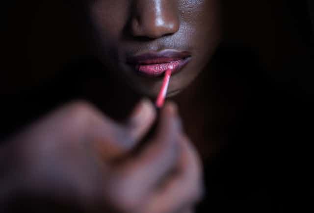 Una joven se pinta los labios.