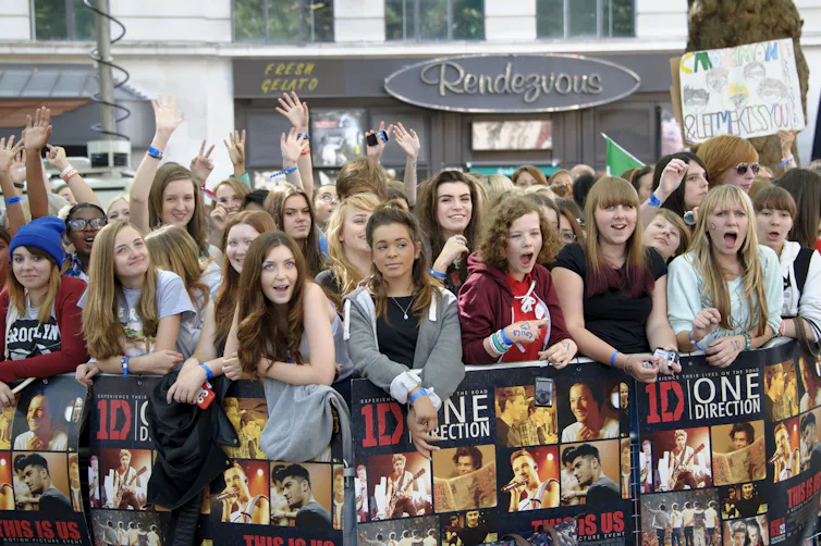 Fangirls behind a barrier.