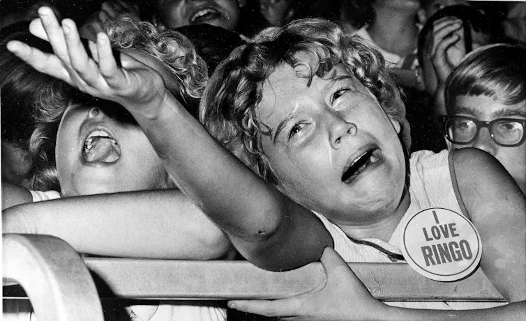 A girl cries, wearing a I Love Ringo badge.