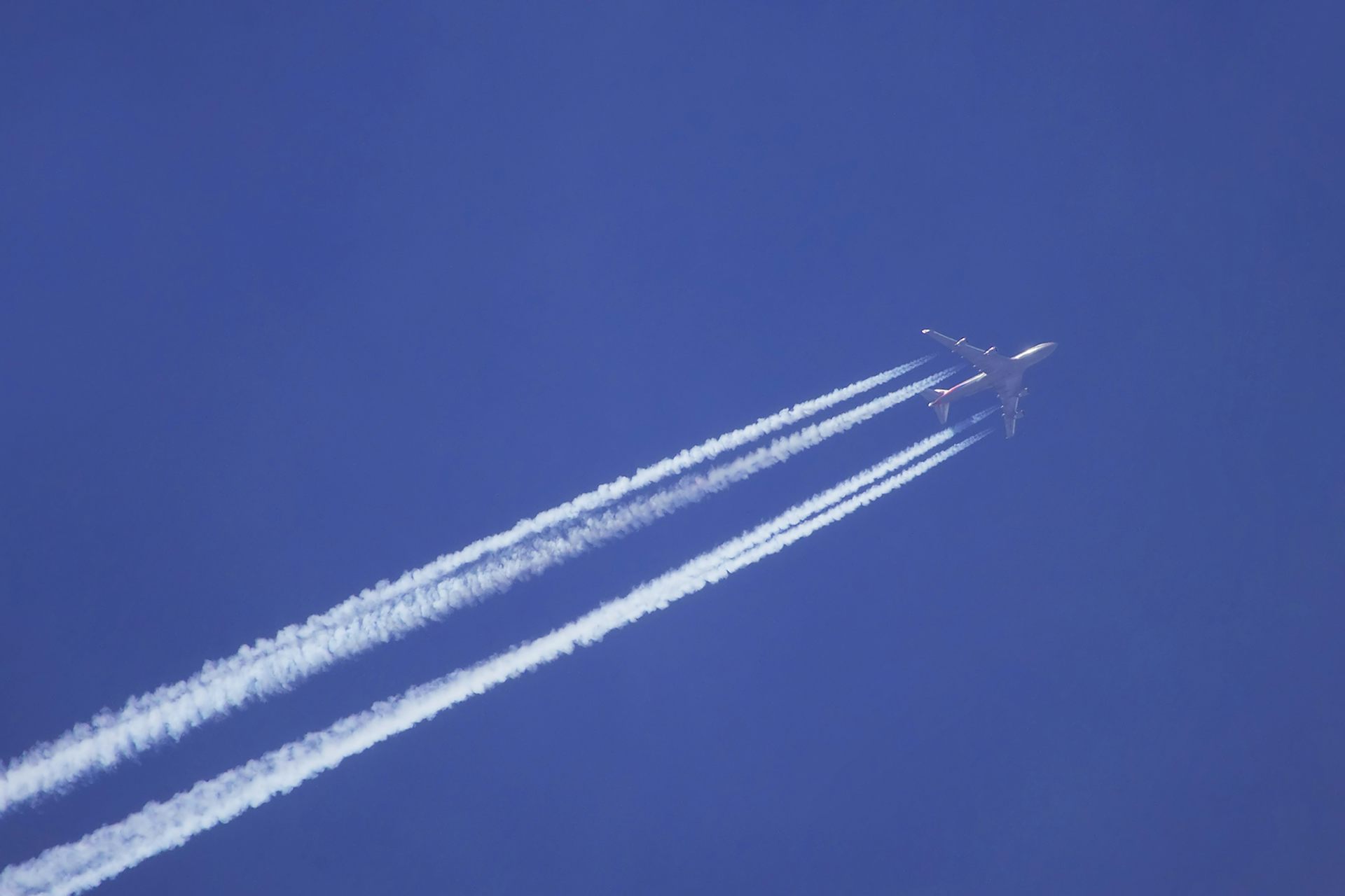 plane in blue sky emitting vapour trails