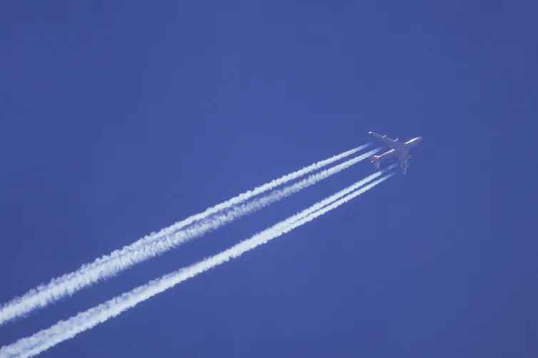 plane in blue sky emitting vapour trails