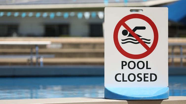 A 'pool closed' sign in front of a swimming pool.