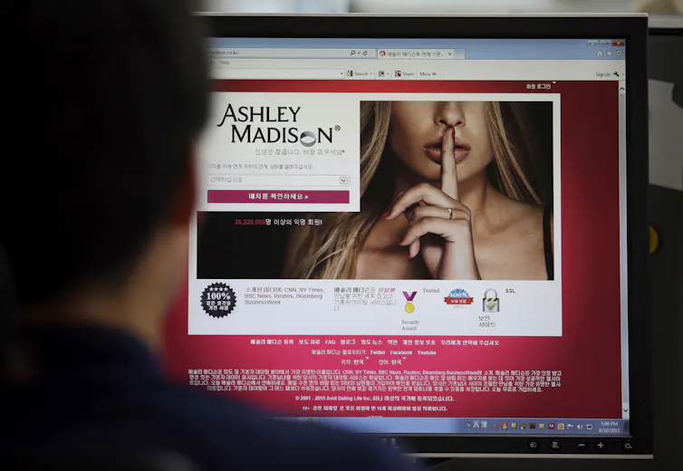 A man looks at a computer screen showing the Ashley Madison website