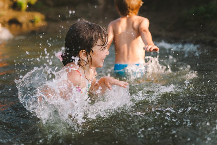 Two children playing in a body of water.