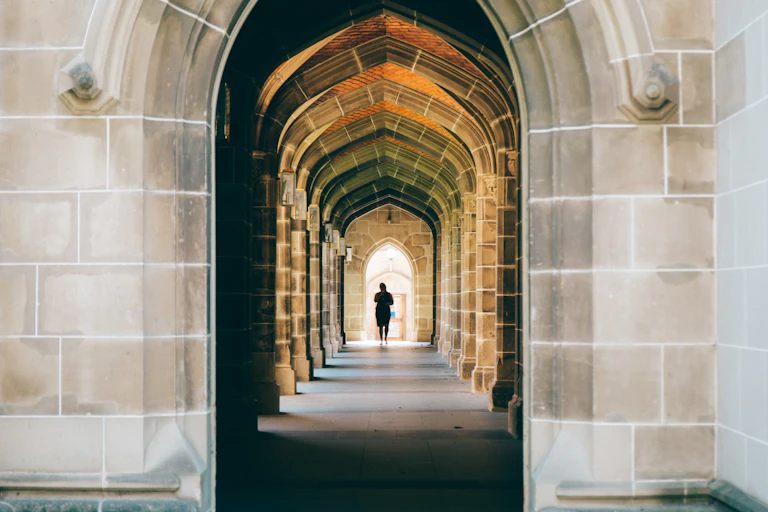 A photo looking through a series of stone archways to a person in the distance.