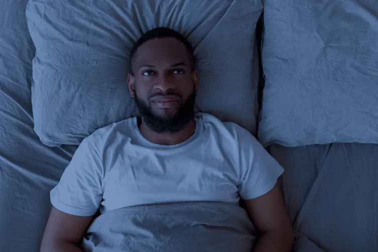 A man lying awake in a bed.