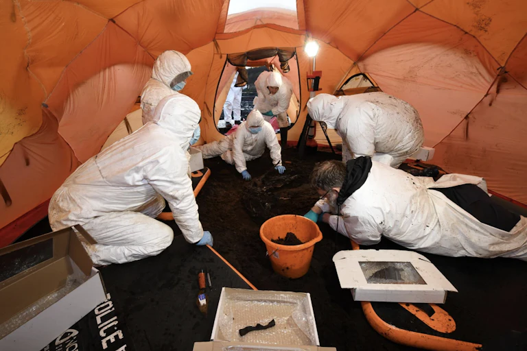 Foresnic archaeologists in a tent excavating a body