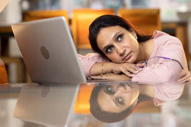 Stressed woman at computer head on arms