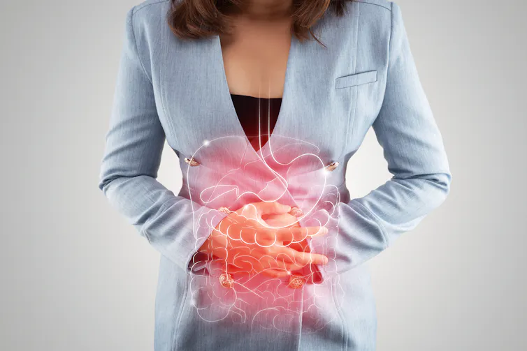 A woman holds her stomach, with a digaram of a digestive system overlaid.