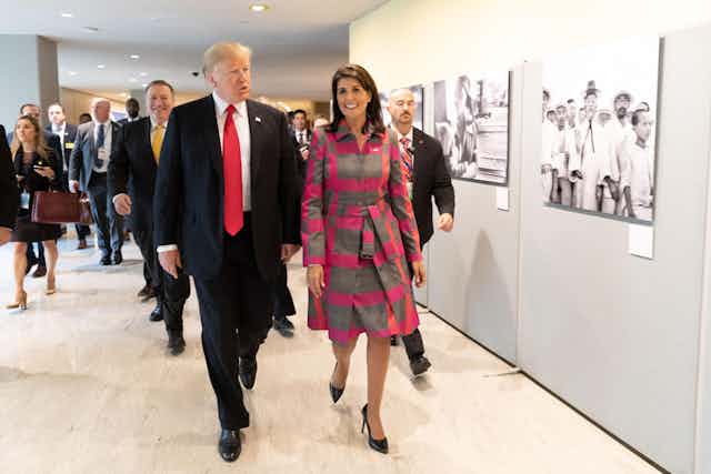 Donald Trump and Nikki Halley walk along a corridor.