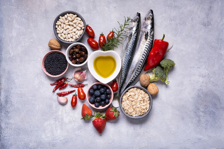 Une composition en fome de coeur est constituée d'aliments crus comme du poisson, des haricots secs et autres graines, des légumes (poivrons, brocolis..), de l'ail, des fraises et de l'huile d'olive.