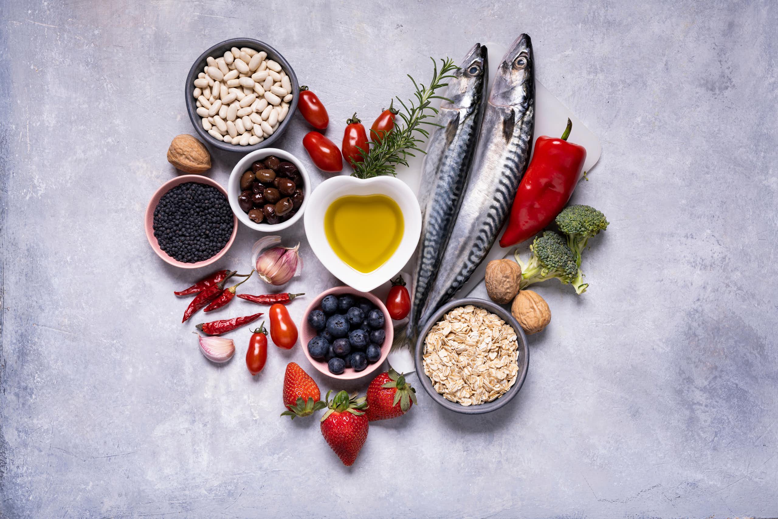Une composition en fome de coeur est constituée d'aliments crus comme du poisson, des haricots secs et autres graines, des légumes (poivrons, brocolis..), de l'ail, des fraises et de l'huile d'olive.